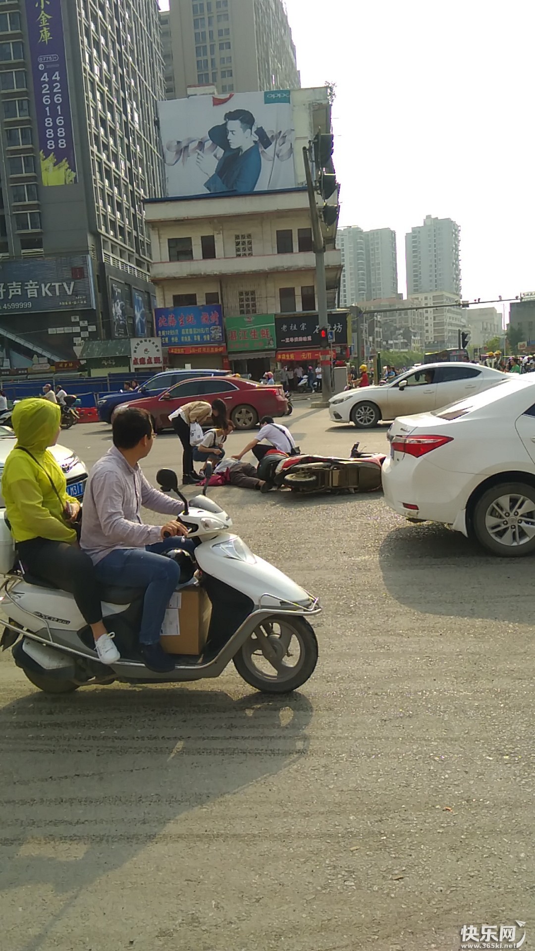 唐人街路口一骑电动车男子不知何因翻车,众人见到后纷纷相帮